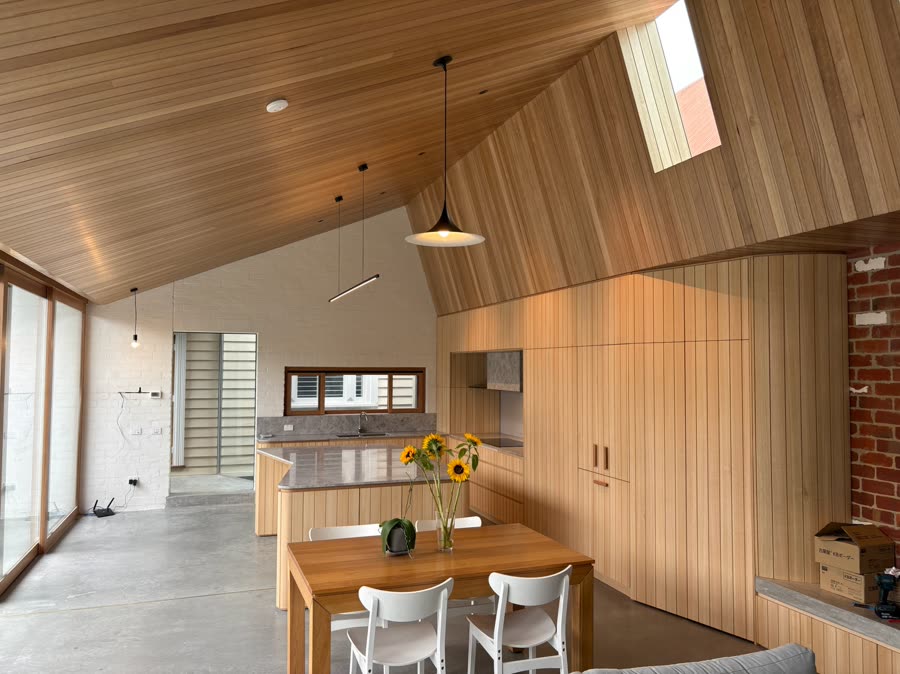 A vaulted timber ceiling over a new kitchen, with the building’s original brickwork left exposed