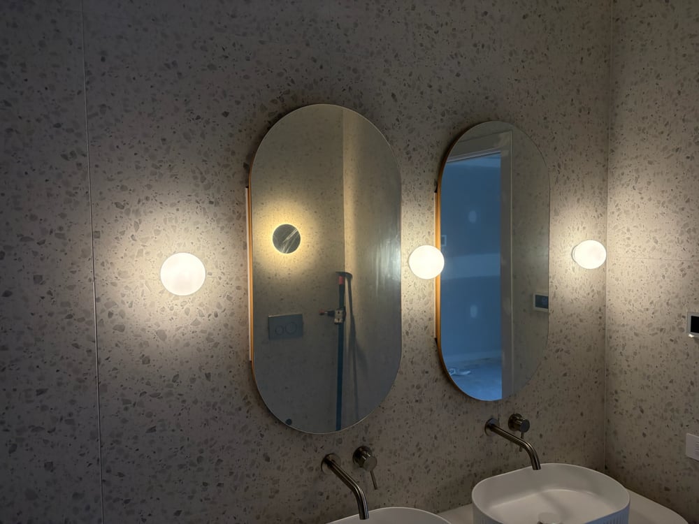 Bathroom with terrazzo walls, oval mirrors and round globe wall sconces
