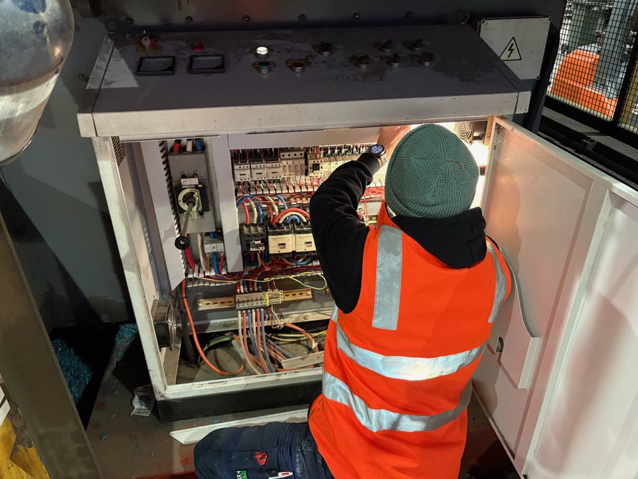 An electrician in hi-vis working inside an open commercial switchboard