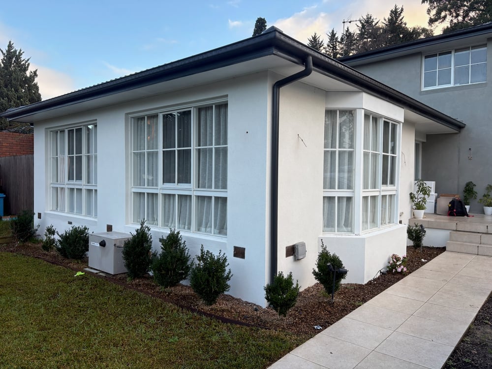 White rendered home exterior with bay windows, exterior points and a garden path