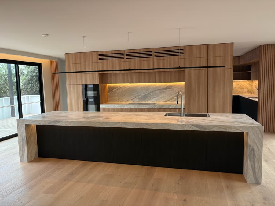 Kitchen with concealed strip lighting washing a stone splashback