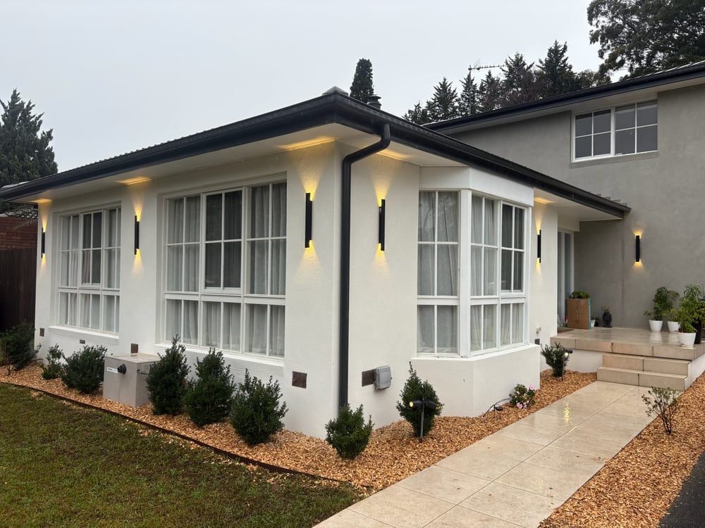 Rendered home facade at dusk with warm up and down LED wall sconces and garden path lights